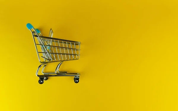 Vista lateral de un carrito de compras vacío aislado sobre fondo amarillo con copyspace — Foto de Stock