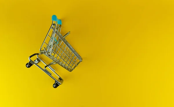 Vista aérea del carro de la compra vacío en fondo amarillo, espacio de copia. — Foto de Stock