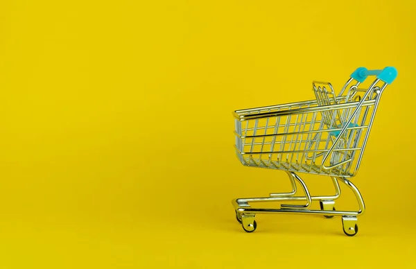 Vista lateral de un carrito de compras vacío sobre fondo amarillo con copyspace. tienda minorista — Foto de Stock