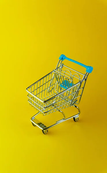 Vista superior vertical de un carrito de compras vacío aislado sobre fondo amarillo con copyspace — Foto de Stock