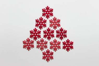 Beyaz arka planda Noel ağacı olarak dizilmiş kırmızı ahşap kar taneleri..