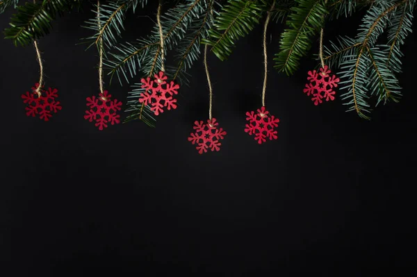 Рождественская Зимняя Открытка Вечнозелеными Ветками Красными Деревянными Снежинками Черном Фоне — стоковое фото