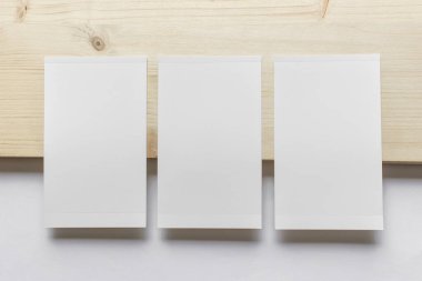 Tahta ve beyaz kağıt zemin üzerinde üç dikey boş fotoğraf kartı olan bir model şablonu.