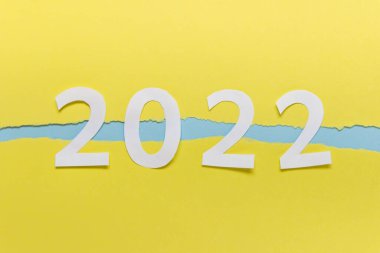 Yıl 2022 sayılar yırtık kenarlı sarı kağıt üzerinde kağıt.