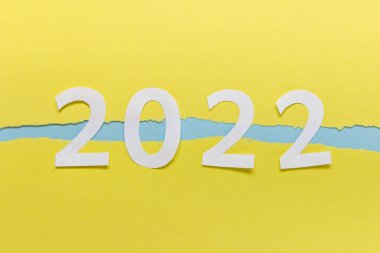 Year 2022 numbers made of paper on yellow paper with ripped edges. clipart