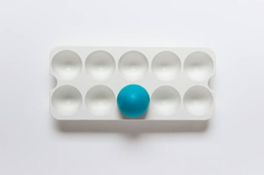 Beyaz plastik standı ve beyaz arka planda tek bir mavi Paskalya yumurtası olan Paskalya tebrik kartı..