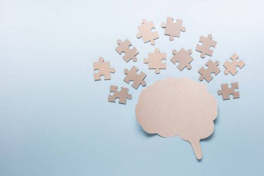 Birçok bulmaca parçasıyla problem çözme kavramı ve mavi arka planda kağıt beyin anahatları. Fotoğraf alanı kopyala.