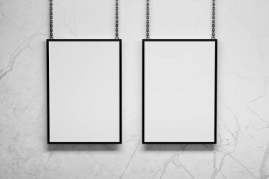 Duvarın yanındaki metal zincirlerde asılı iki dikey A4 çerçeve. 3d illüstrasyon.