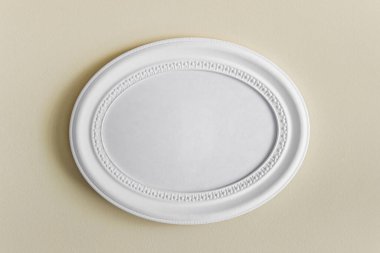 Oval beyaz desenli fotoğraf çerçeveli model şablonu. Sarı duvarda boş bir kopya alanı asılı..