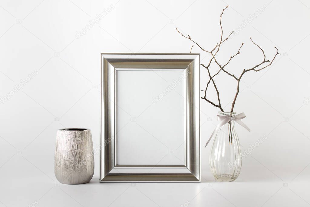 Silver wide frame with blank copy space, silver pot, glass vase and dry plant branch.