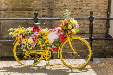 Yellow bicycle decorated with flowers at the canal in Gouda, Netherlands clipart