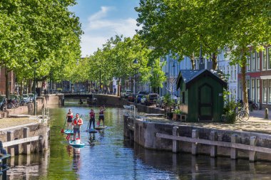 Young people paddling through the canals of Gouda, Netherlands clipart