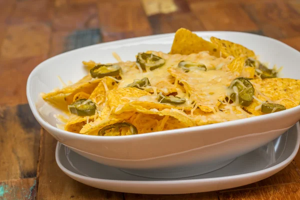 Nachos with cheese and jalapenos in a white bowl — Stok fotoğraf