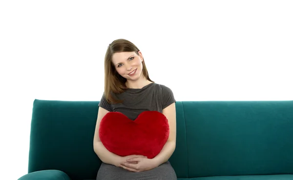 Woman smiling with heart shaped pillow — Stock Photo, Image