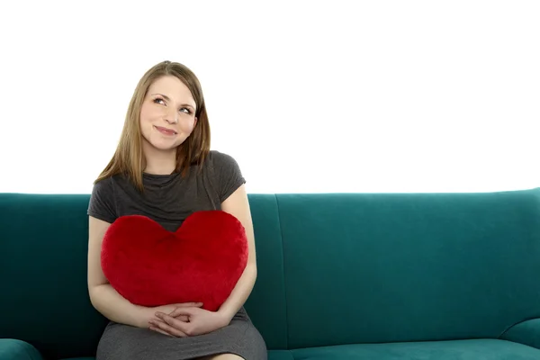 Woman smiling with heart shaped pillow — Stock Photo, Image