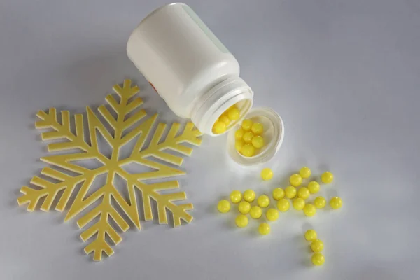 Sarı haplar ve kar tanesi şeklinde C vitamini.