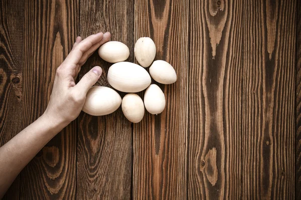 Wood toy eggs, hands, brown wood background