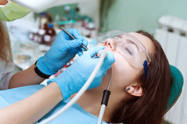 Dentista curando a una paciente femenina — Foto de Stock