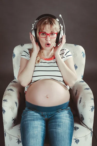 Mujer embarazada escuchando música en los auriculares — Foto de Stock