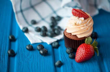 Mavi ahşap masa üzerinde yaz meyveleri ile cupcakes