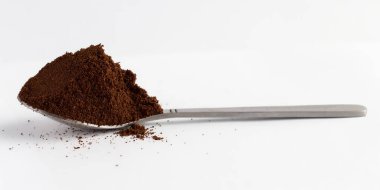 Beyaz arka planda öğütülmüş kahve kaşığı. 