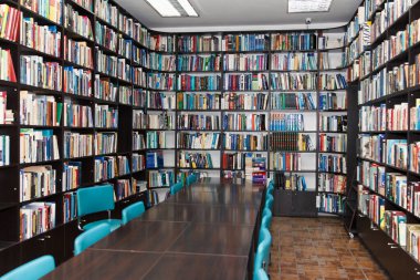 Kütüphanedeki okuma odasındaki raflarda bir sürü renkli kitap yatıyor. Yazı