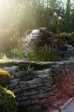 Parkta taştan yapılmış fıskiyeli güzel bir gölet.