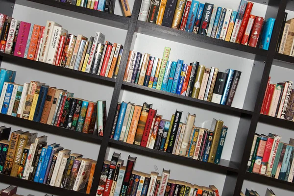 Kütüphanedeki okuma odasında raflarda bir sürü renkli kitap var.