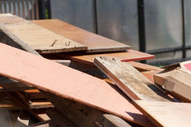 Karman çorman bir odun yığını, atılmış kalaslar, inşaat enkazı. Parlak gün ışığı, kahverengi turuncu renklerdeki farklı dokuları ortaya çıkarır. Yıkım, yenileme, geri dönüşüm kavramları için.