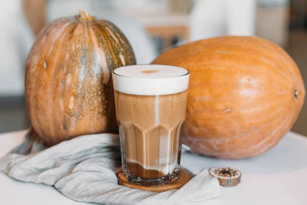 Pumpkin latte in a tall clear glass. Hot autumn drink.