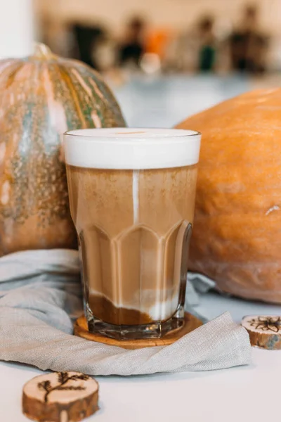 Pumpkin latte in a tall clear glass, hot autumn drink