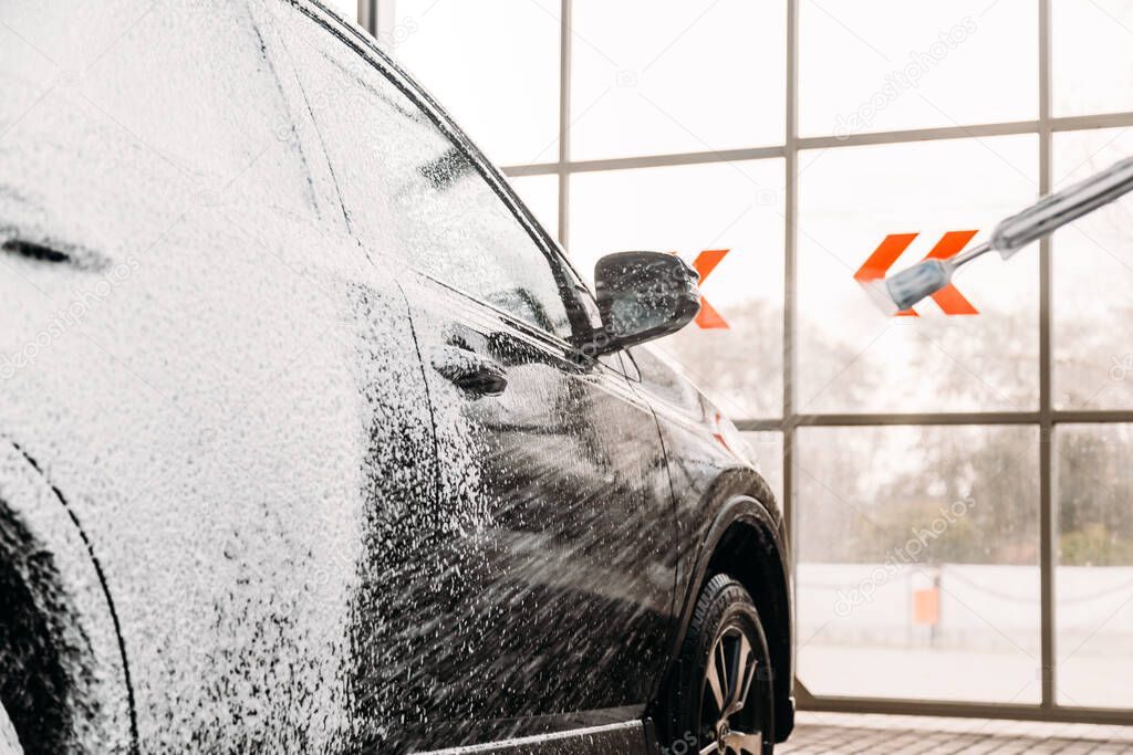Woman washing his car in a self-service car wash station.Car wash self-service. 