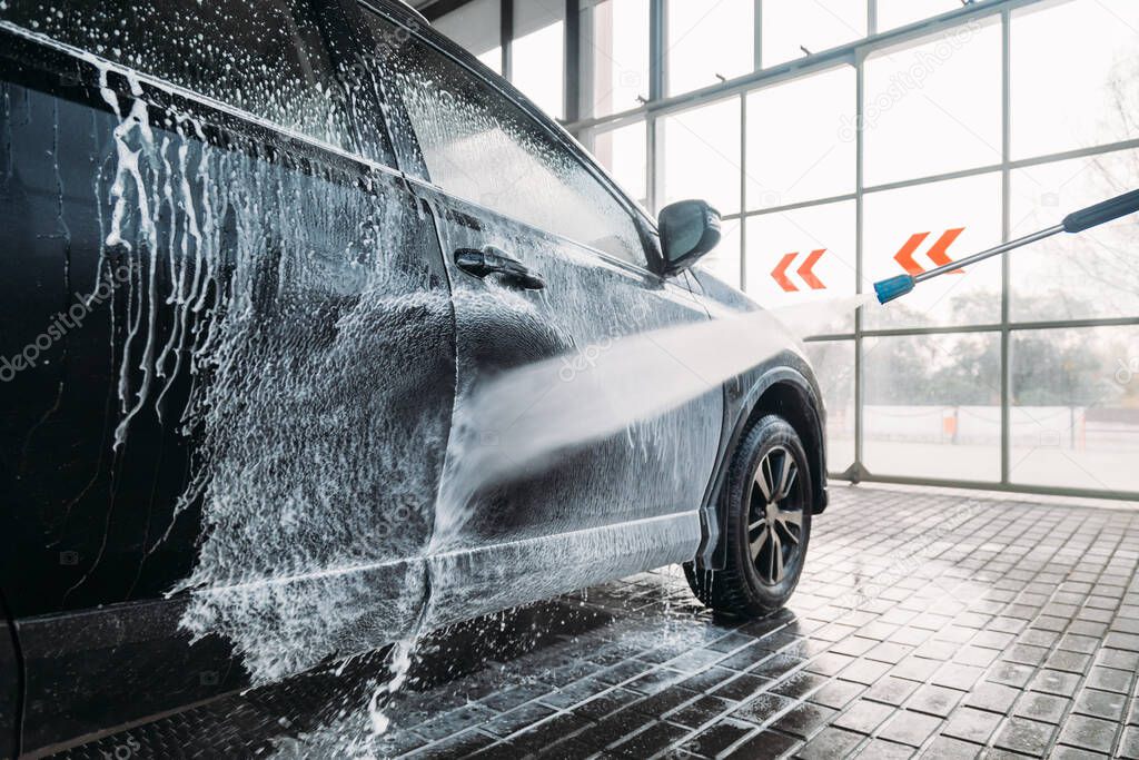 Woman washing his car in a self-service car wash station.Car wash self-service. 