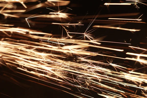 Flusso luminoso di scintille al buio. Fuoco scintille su uno sfondo scuro — Foto Stock