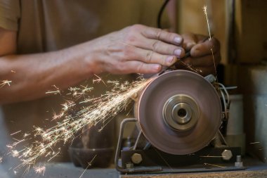 İnsan bir makinede metal bir bıçağı bileyebilir. Adam atölyesinde üretim yapıyor..