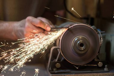 İnsan bir makinede metal bir bıçağı bileyebilir. Adam atölyesinde üretim yapıyor..