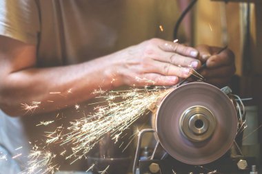 İnsan bir makinede metal bir bıçağı bileyebilir. Adam atölyesinde üretim yapıyor..