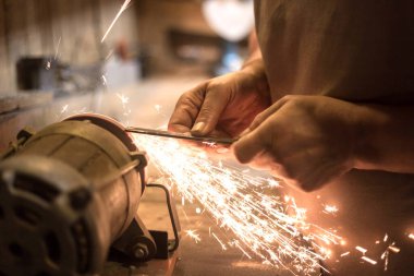 İnsan bir makinede metal bir bıçağı bileyebilir. Adam atölyesinde üretim yapıyor..