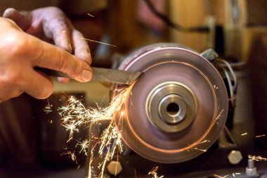 İnsan bir makinede metal bir bıçağı bileyebilir. Adam atölyesinde üretim yapıyor..