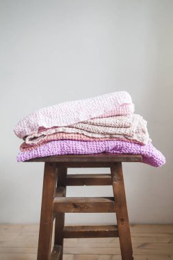 Doğal çarşaf ve pamuktan farklı renkte havlular bir sandalyenin üzerinde.