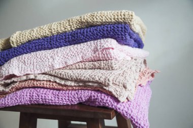 Doğal çarşaf ve pamuktan farklı renkte havlular bir sandalyenin üzerinde.