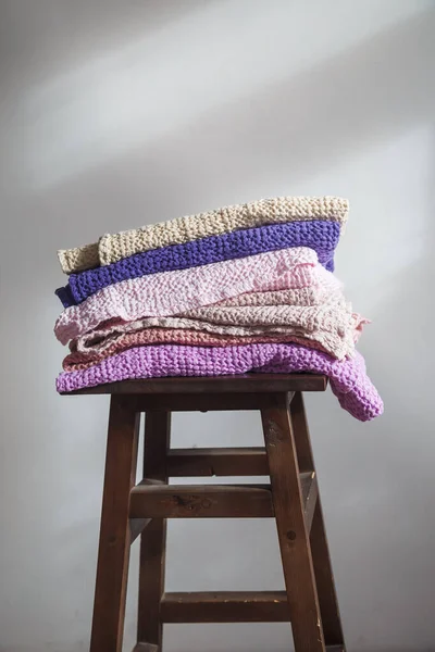 Doğal çarşaf ve pamuktan farklı renkte havlular bir sandalyenin üzerinde.