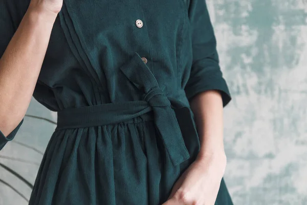 Wunderschönes grünes Cordkleid auf einem Mädchen in Nahaufnahme. Hand am Gürtel lizenzfreie Stockbilder
