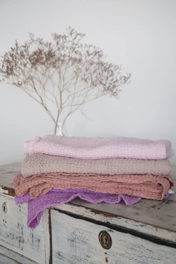 Beyaz bir çekmece üzerindeki doğal pamuk kumaşlarından farklı renkte havlular.