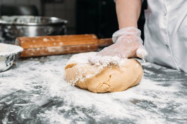 Kadın eli, hamur yoğurur bir parça hamur ve fırın tabağının yanında. 
