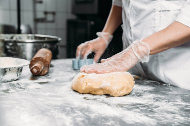 Kadın eli, hamur yoğurur bir parça hamur ve fırın tabağının yanında. 