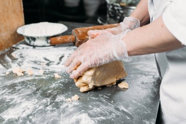 Kadın eli bir hamur yaprağını yuvarlar masanın üzerinde bir mangır ve bir fırın tabağının yanında merdane ile. 