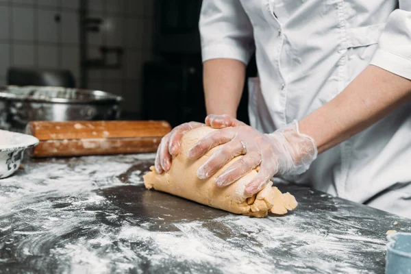 Kadın eli, hamur yoğurur bir parça hamur ve fırın tabağının yanında. 