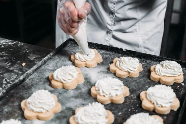 Chefs hands with pastry bag squeezing out cream dough for baking
