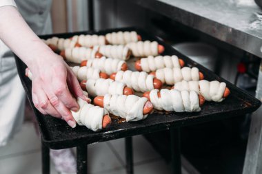 Hamur içinde sosis yapma süreci. Şef pişmiş sosisle birlikte yemek hazırlar. 